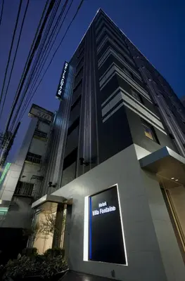 a tall building with a sign in front of it at Villa Fontaine Tokyo Shinjuku in Tokyo