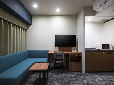 a room with a blue couch and a table and a tv at Villa Fontaine Tokyo Ueno Okachimachi in Tokyo