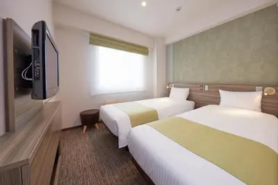 a hotel room with two beds and a flat screen tv at Villa Fontaine Tokyo Nihombashi Hakozaki in Tokyo