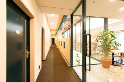 a hallway in a building with glass doors and a plant at Villa Fontaine Tokyo Nihombashi Hakozaki in Tokyo