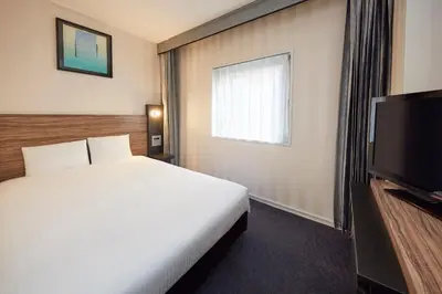 a hotel room with a bed and a flat screen tv at Villa Fontaine Tokyo Nihombashi Hakozaki in Tokyo