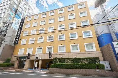 a yellow building with white windows on a street at Villa Fontaine Tokyo Jimbocho in Tokyo