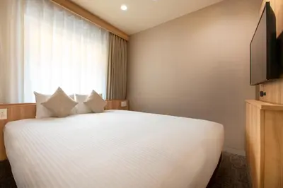 a bedroom with a large white bed with a window at Villa Fontaine Tokyo Jimbocho in Tokyo