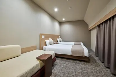 a hotel room with two beds and a couch at Villa Fontaine Tokyo Jimbocho in Tokyo