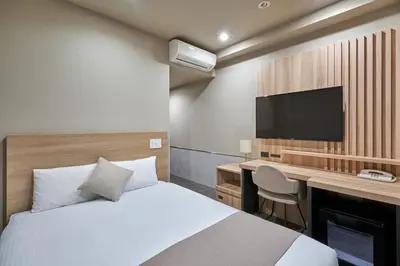 a bedroom with a bed and a desk and a tv at Villa Fontaine Tokyo Jimbocho in Tokyo