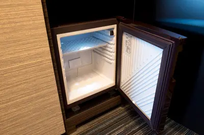 a small refrigerator with its door open in a cabinet at Villa Fontaine Tokyo Jimbocho in Tokyo