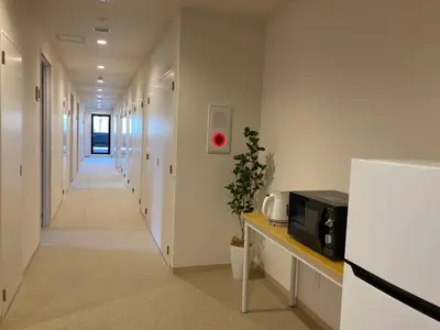 a corridor of a hallway with a microwave on a counter at Tokyo Ueno Youth Hostel in Tokyo