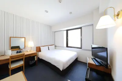 a hotel room with a bed and a desk and a television at Smile Hotel Nihombashi Mitsukoshimae in Tokyo