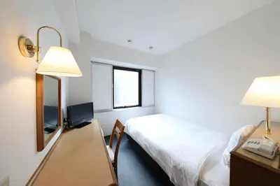 a room with a bed and a desk with a mirror at Smile Hotel Nihombashi Mitsukoshimae in Tokyo