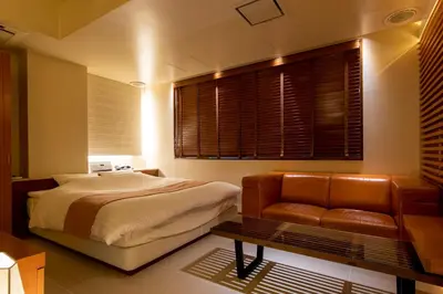 a bedroom with a bed and a couch and windows at HOTEL APERTO (Adult Only) in Tokyo