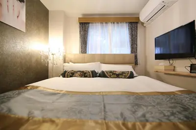a bedroom with a large bed with a flat screen tv at SHINJUKU GLOBAL HOTEL in Tokyo