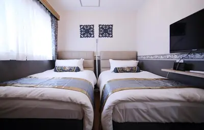 two twin beds in a room with a tv at SHINJUKU GLOBAL HOTEL in Tokyo