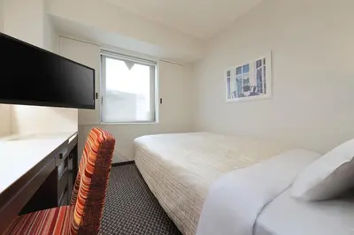a bedroom with a bed and a desk with a television at Keio Presso Inn Nihonbashi Kayabacho in Tokyo