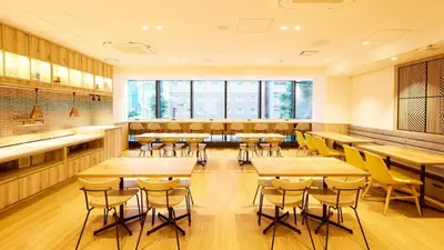 a restaurant with wooden tables and yellow chairs at hotel MONday Akihabara Asakusabashi in Tokyo