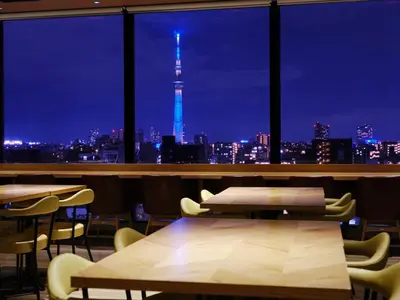 a restaurant with a view of the eiffel tower at night at hotel MONday Premium Ueno Okachimachi in Tokyo