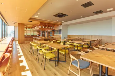 a restaurant with wooden tables and yellow chairs at hotel MONday Premium Ueno Okachimachi in Tokyo