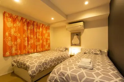 a bedroom with two beds and an orange curtain at Cross Bridge Ikebukuro in Tokyo