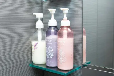 three bottles sitting on a shelf in a bathroom at Cross Bridge Ikebukuro in Tokyo
