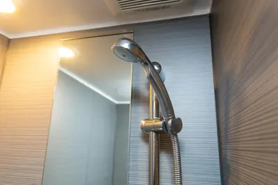 a shower head in a bathroom with a mirror at Cross Bridge Ikebukuro in Tokyo