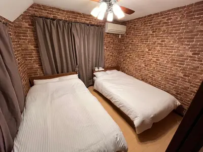two beds in a room with a brick wall at Hotel EL Shinjuku 1 free parking in Tokyo