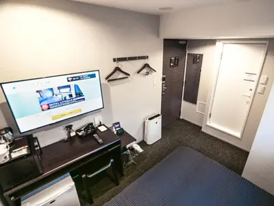 a hotel room with a tv and a desk and a bathroom at HOTEL LiVEMAX Tokyo Kanda-Ekimae in Tokyo