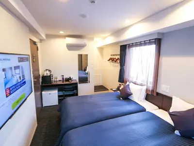 a hotel room with a blue bed and a tv at HOTEL LiVEMAX Tokyo Kanda-Ekimae in Tokyo