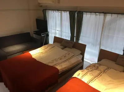 two beds in a room with a couch and window at G&R House 102 in Tokyo