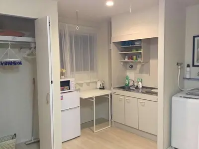 a small kitchen with white cabinets and a white refrigerator at \u99c5\u8fd1-JR\u5c0f\u5ca9\u99c5\u307e\u3067\u5f92\u6b693\u5206-Leo\u5c0f\u5ca9 101 in Tokyo