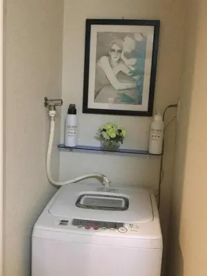 a washing machine in a bathroom with a picture on the wall at \u99c5\u8fd1-JR\u5c0f\u5ca9\u99c5\u307e\u3067\u5f92\u6b693\u5206-Leo\u5c0f\u5ca9 101 in Tokyo