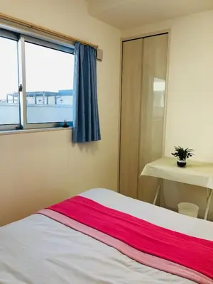a bedroom with a bed with a window and a table at Takara House in Tokyo