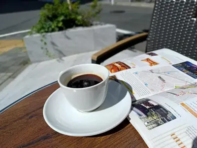 a cup of coffee sitting on a table next to a newspaper at Akasaka Urban Hotel Annex in Tokyo