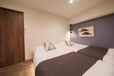 a bedroom with two beds and a wooden door at PREMIER suite Shinjuku West 2F in Tokyo