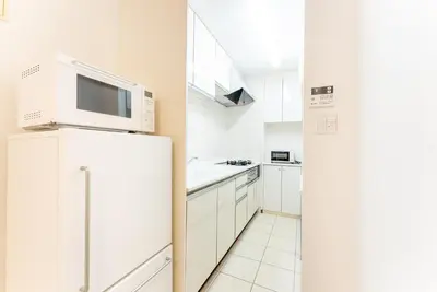 a white kitchen with a microwave on top of a refrigerator at Minami-Aoyama-1st in Tokyo
