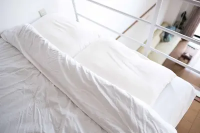 an unmade bed with white sheets in a room at MINIMAL SHIMOKITA Stylish Loft or Studio Apt in Tokyo