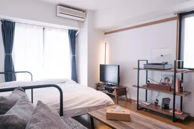 a bedroom with a bed and a tv and a couch at MINIMAL SHIMOKITA Stylish Loft or Studio Apt in Tokyo