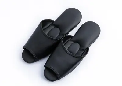a pair of black flip flops on a white background at APA Hotel Ginza Shintomicho Ekimae in Tokyo