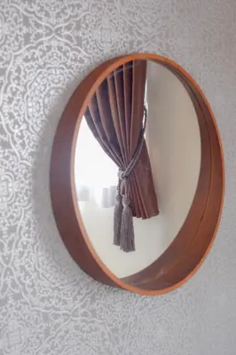 a round mirror hanging on a wall with a curtain at FINOA Residential Suite Kagurazaka in Tokyo