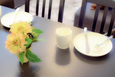 a table with plates and a glass of milk and flowers at FINOA Residential Suite Kagurazaka in Tokyo