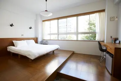 a bedroom with a bed and a desk and a window at No Service Hotel in Tokyo