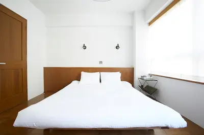 a bedroom with a large bed with white sheets at No Service Hotel in Tokyo