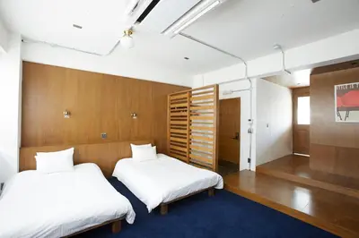 two beds in a room with wood paneling at No Service Hotel in Tokyo