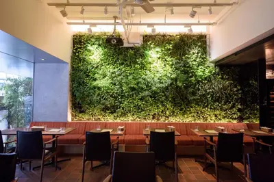 a large green wall in a restaurant with tables and chairs at Roppongi Hotel S in Tokyo
