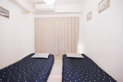 two beds in a room with white walls at Tookin house \u6c60\u888b in Tokyo