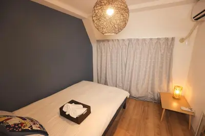 a small bedroom with a bed and a table and a lamp at Tookin house \u6c60\u888b in Tokyo