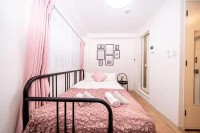 a small bedroom with a bed with pink sheets and pillows at Tookin house \u6c60\u888b in Tokyo