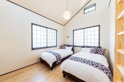 two beds in a room with two windows at YADOYA Sennokaze in Tokyo