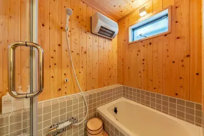 a bathroom with a tub and a toilet and a window at YADOYA Sennokaze in Tokyo