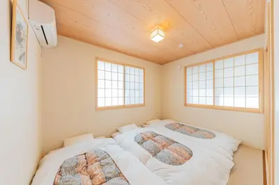 two beds in a small room with two windows at YADOYA Sennosato in Tokyo