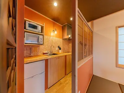 a kitchen with orange walls and wooden cabinets at YADOYA Sennosato in Tokyo