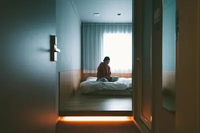a person sitting on a bed in a room at LANDABOUT TOKYO in Tokyo